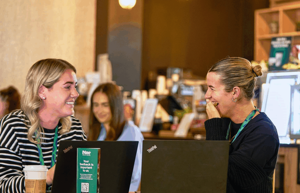 “Two people in a café setting, one smiling and one laughing".